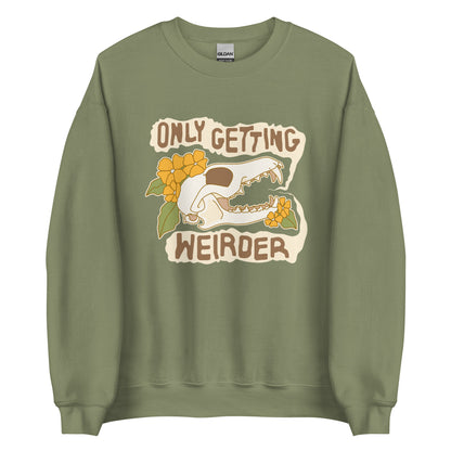 An olive green crewneck sweatshirt featuring an illustration of a fox skull surrounded by yellow flowers. Wobbly speech bubbles are coming from the fox's mouth. The text inside the bubbles reads "ONLY GETTING WEIRDER".