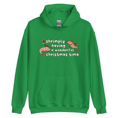 A green hooded sweatshirt featuring an illustration of two festive shrimp - one with a Santa hat, and one with reindeer antlers. Text between the shrimp reads "shrimply having a wonderful Christmas time".