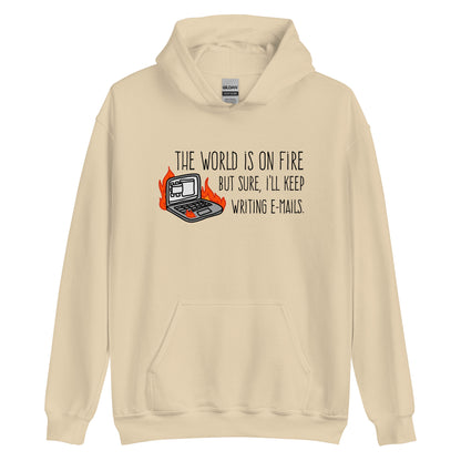 A tan hooded sweatshirt featuring a squiggly illustration of a laptop that is on fire. Text alongside the laptop reads "the world is on fire but sure, I'll keep writing e-mails."