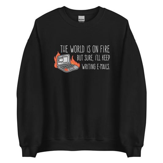 A black crewneck sweatshirt featuring a squiggly illustration of a laptop that is on fire. Text alongside the laptop reads "the world is on fire but sure, I'll keep writing e-mails."