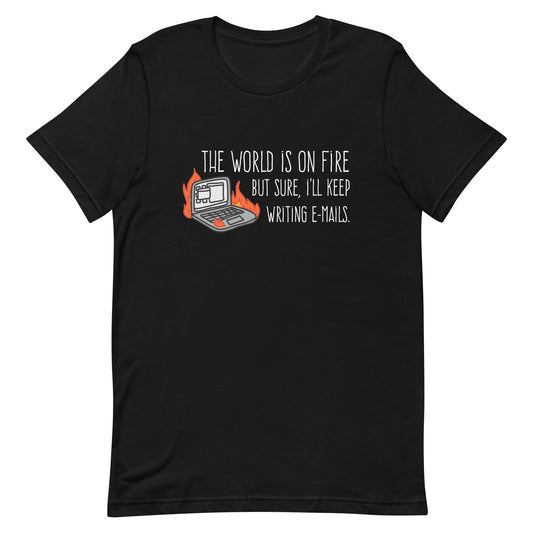 A black crewneck t-shirt featuring a squiggly illustration of a laptop that is on fire. Text alongside the laptop reads "the world is on fire but sure, I'll keep writing e-mails."
