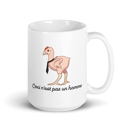 A 15 ounce ceramic mug featuring an illustration of a featherless chicken wearing a tie. Text underneath the chicken reads "Ceci n'est pas un homme" in a cursive font.