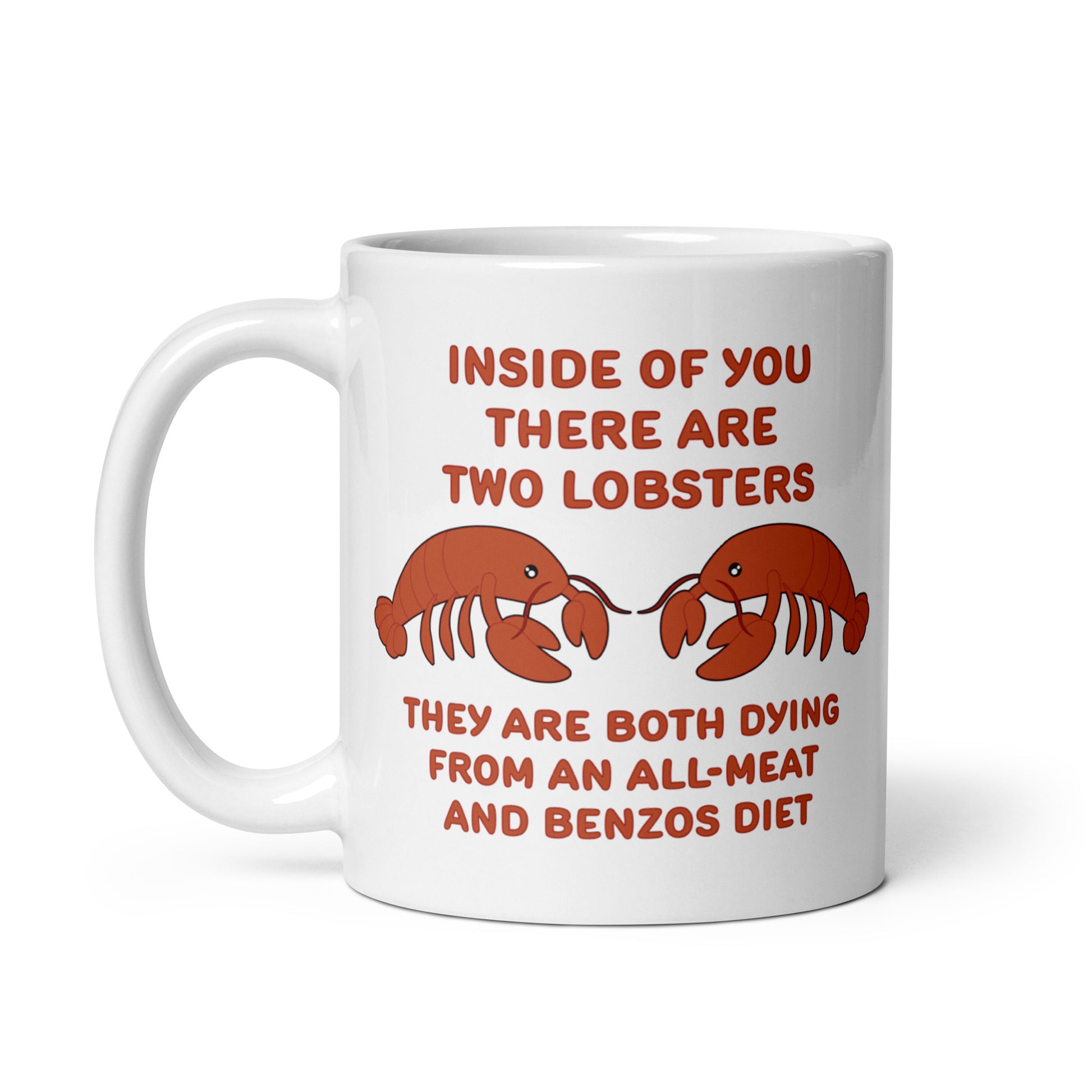 A white 11 ounce ceramic mug featuring an illustration of two lobsters. Text around the lobsters reads "Inside of you there are two lobsters." "They are both dying from an all-meat and benzos diet."