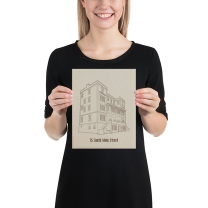 A woman holding an 8 inch by 10 inch print. The print is a sepia tone illustration of a building. The building is labeled "75 South Main Street"