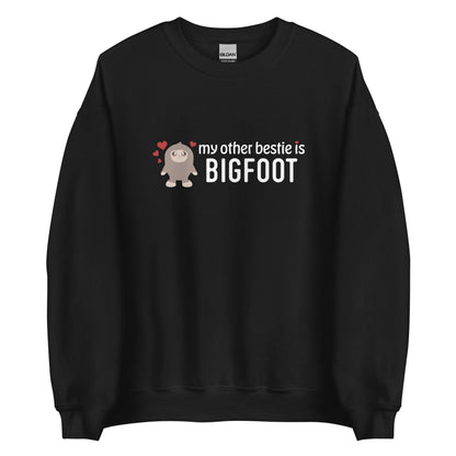 A black crewneck sweatshirt featuring a cutesy illustration of Bigfoot surrounded by hearts. Text to the side of Bigfoot reads "my other bestie is Bigfoot"