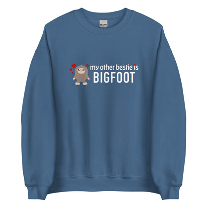 A blue-grey crewneck sweatshirt featuring a cutesy illustration of Bigfoot surrounded by hearts. Text to the side of Bigfoot reads "my other bestie is Bigfoot"