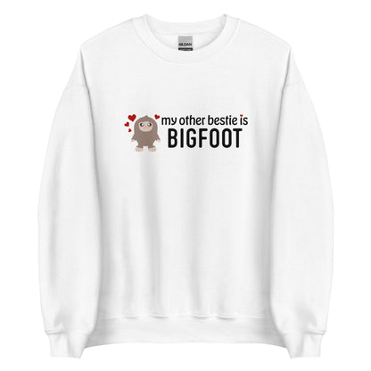 A white crewneck sweatshirt featuring a cutesy illustration of Bigfoot surrounded by hearts. Text to the side of Bigfoot reads "my other bestie is Bigfoot"