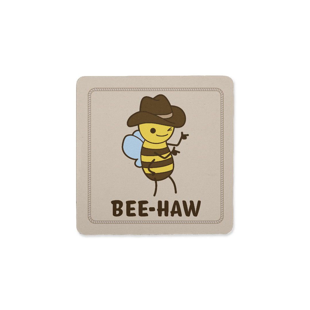 A square coaster with an image of a bee in a cowboy hat. The bee is winking and holding up "finger guns". Text below the bee reads "Bee-Haw"