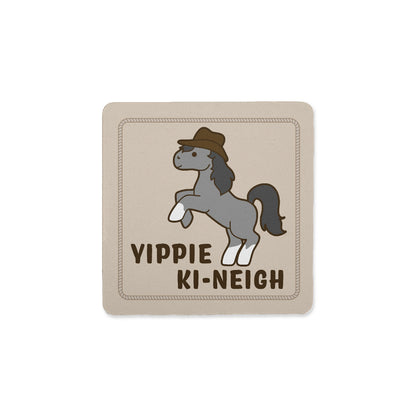 A square coaster with an image of a rearing gray and white pony wearing a cowboy hat. Text below the pony reads "Yippie ki-neigh"