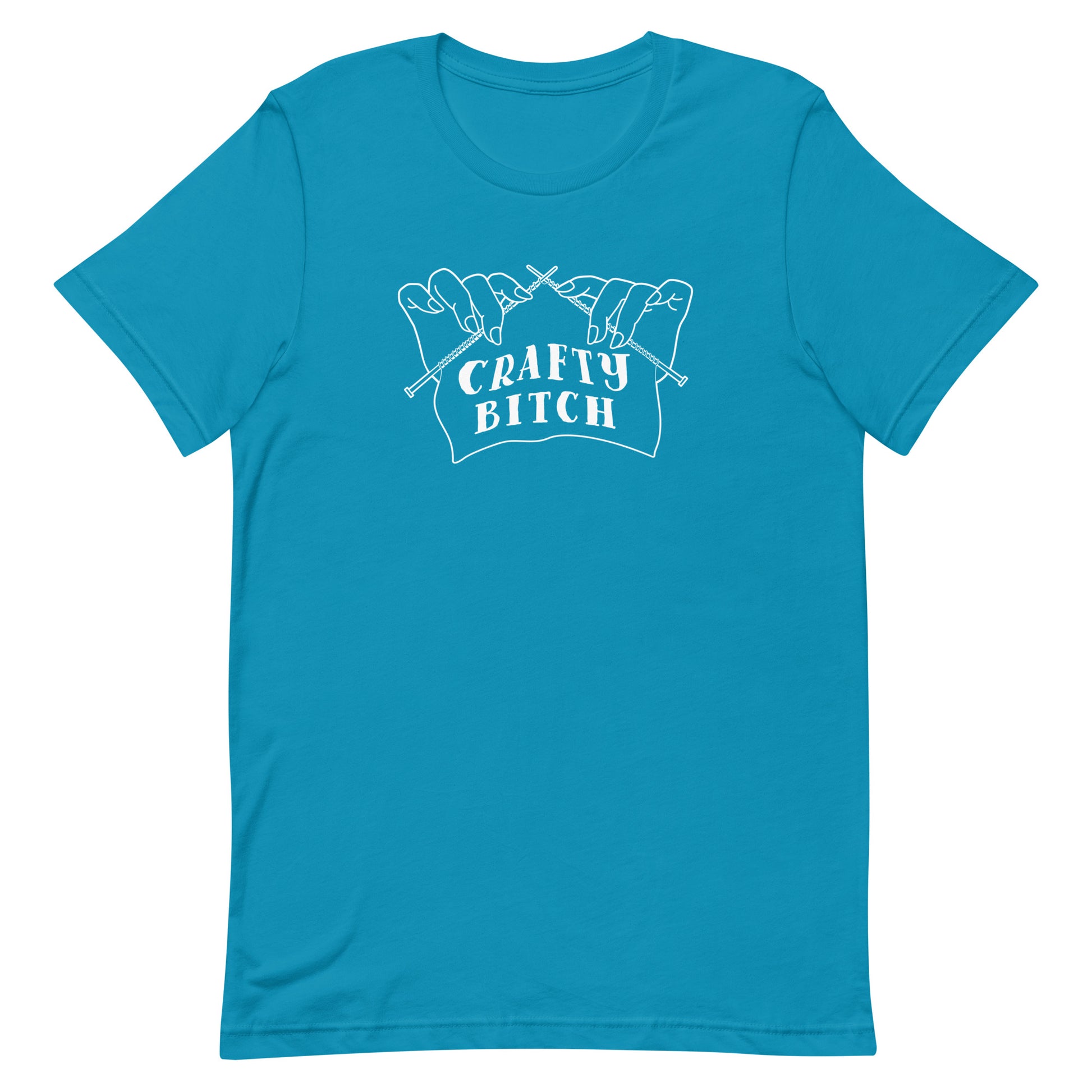 A blue crewneck t-shirt featuring a single-color illustration of a pair of hands holding knitting needles. Fabric on the needles features text that reads "crafty bitch".