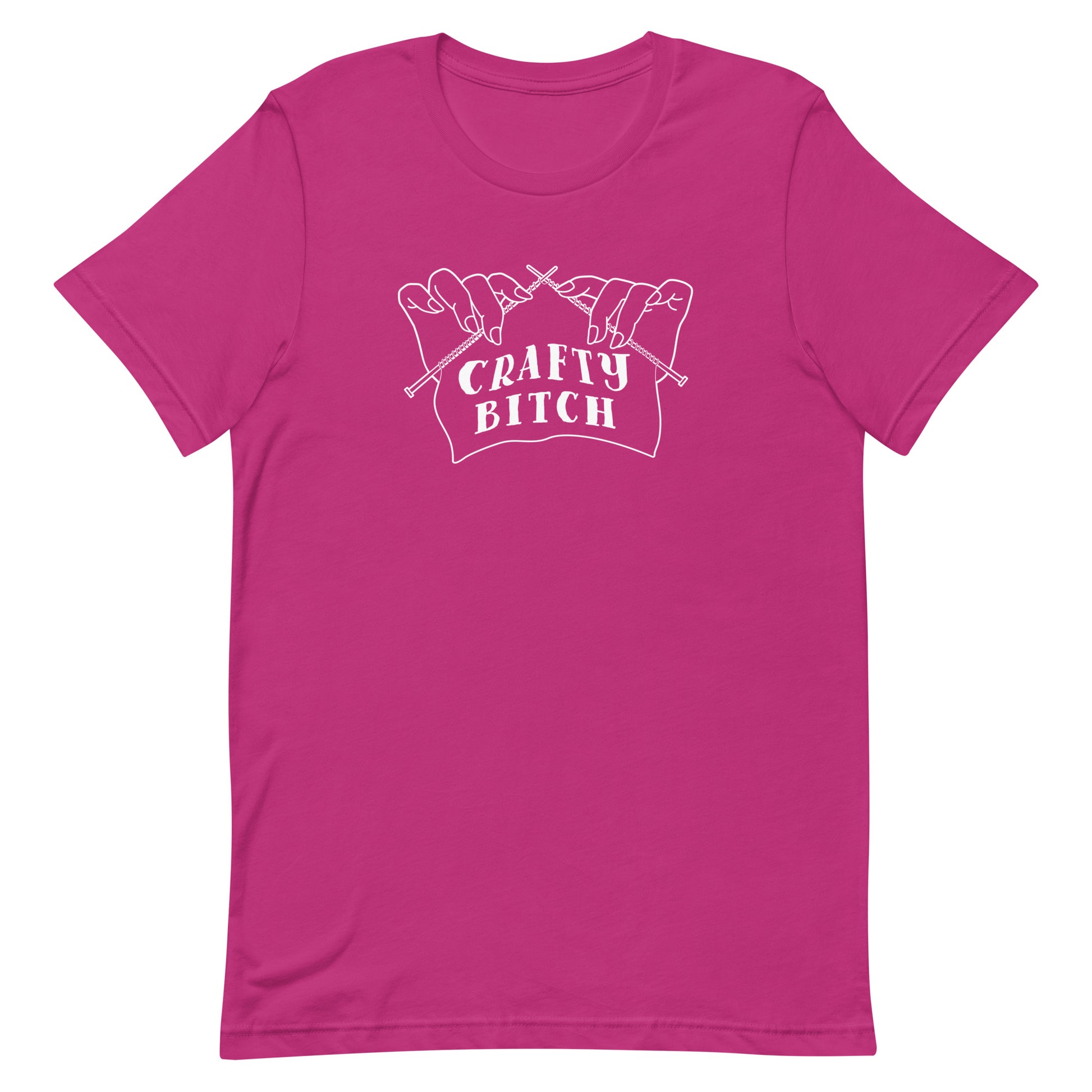 A magenta crewneck t-shirt featuring a single-color illustration of a pair of hands holding knitting needles. Fabric on the needles features text that reads "crafty bitch".