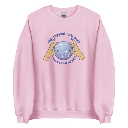 A light pink crewneck sweatshirt with a picture of hands on a crystal ball and text reading "My crystal ball says you're full of shit"