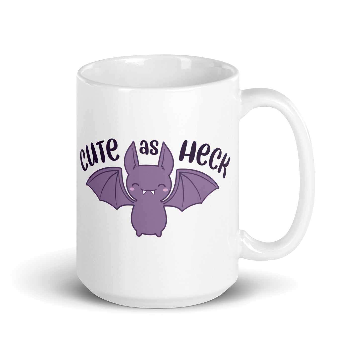 A 15 ounce white ceramic mug featuring an illustration of a smiling purple bat. Above the bat is text that reads "Cute As Heck"