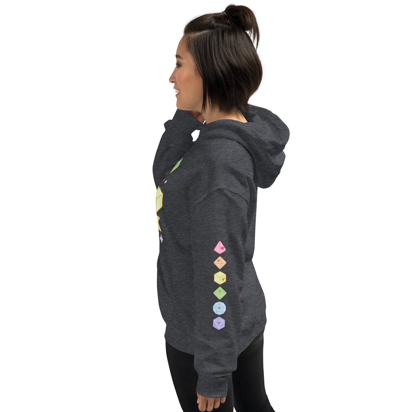A woman wearing a hooded dark grey sweatshirt, facing to the left. On the sleeve of the sweatshirt is the image of six polyhedral dice in pastel rainbow colors.