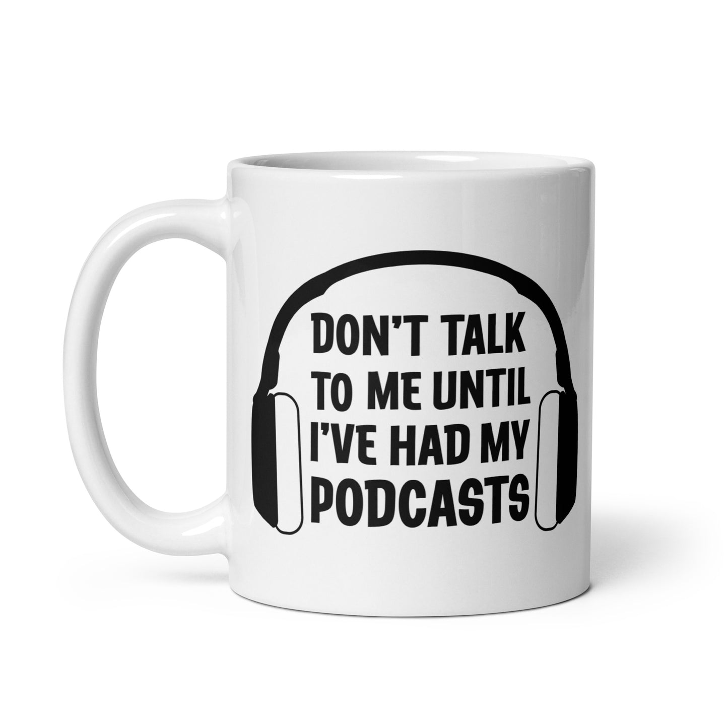 A white 11 ounce ceramic coffee mug featuring an image of headphones surrounding text reading "Don't talk to me until I've had my podcasts"