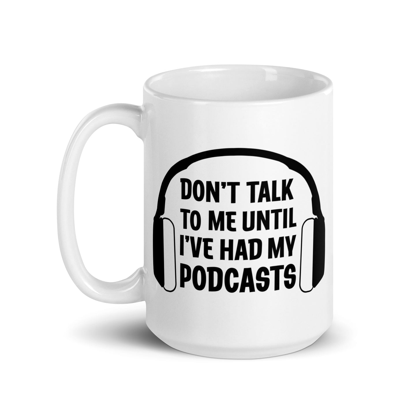 A white 15 ounce ceramic coffee mug featuring an image of headphones surrounding text reading "Don't talk to me until I've had my podcasts"