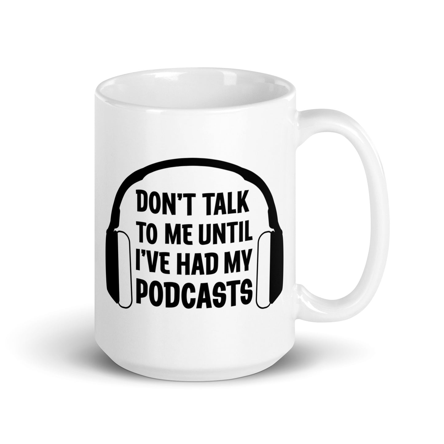 A white 15 ounce ceramic coffee mug featuring an image of headphones surrounding text reading "Don't talk to me until I've had my podcasts"