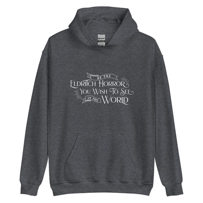 A dark heather grey hooded sweatshirt featuring white text in an old-fashioned style on the chest. The text reads "Be the Eldritch Horror You Wish To See In The World".
