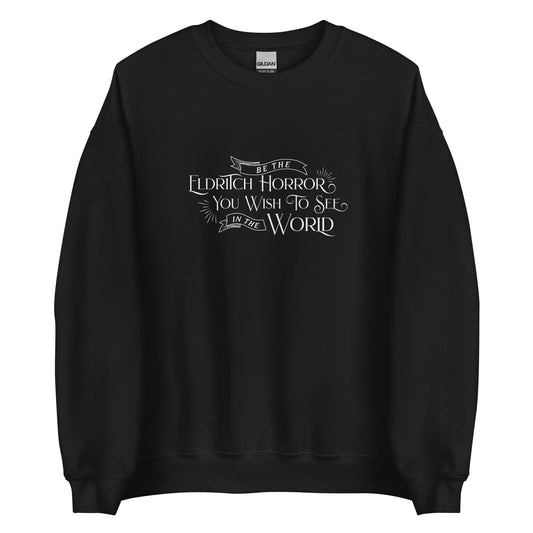 A black crewneck sweatshirt with white old-fashioned text that reads "Be The Eldritch Horror You Wish To See In The World"