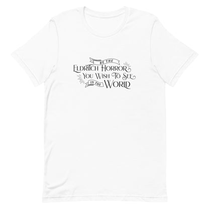 A white crewneck t-shirt with white text in an old-fashioned style that reads "Be The Eldritch Horror You Wish To See In The World"