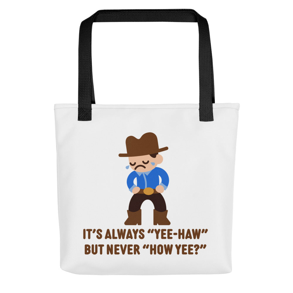 A white canvas tote bag with black handles featuring an illustration of a crying cowboy wearing a blue shirt. Text alongside the cowboy reads "It's always "yee-haw" but never "How yee?""