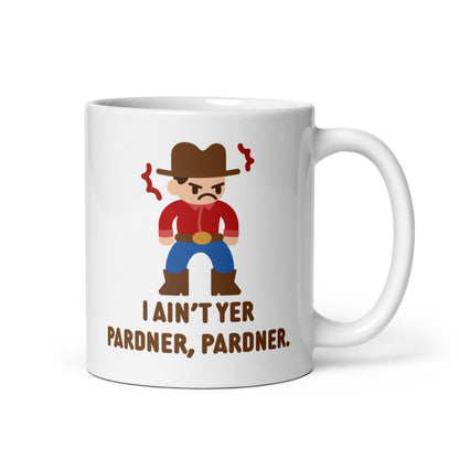 A white 11 ounce ceramic coffee mug featuring an illustration of a grumpy cowboy wearing a red shirt. Text beneath the cowboy reads "I ain't yer pardner, pardner."