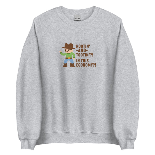 A grey crewneck sweatshirt featuring an illustration of a confused-looking cowboy wearing a green shirt. Text to the right of the cowboy reads "Rootin' AND tootin'?! In this economy?!"