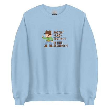 A light blue crewneck sweatshirt featuring an illustration of a confused-looking cowboy wearing a green shirt. Text to the right of the cowboy reads "Rootin' AND tootin'?! In this economy?!"
