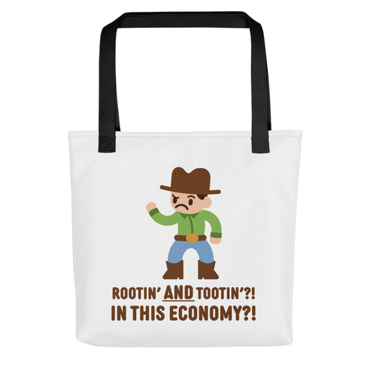 A white canvas tote bag with black handles featuring an illustration of a confused-looking cowboy wearing a green shirt. Text underneath the cowboy reads "Rootin' AND tootin'?! In this economy?!"
