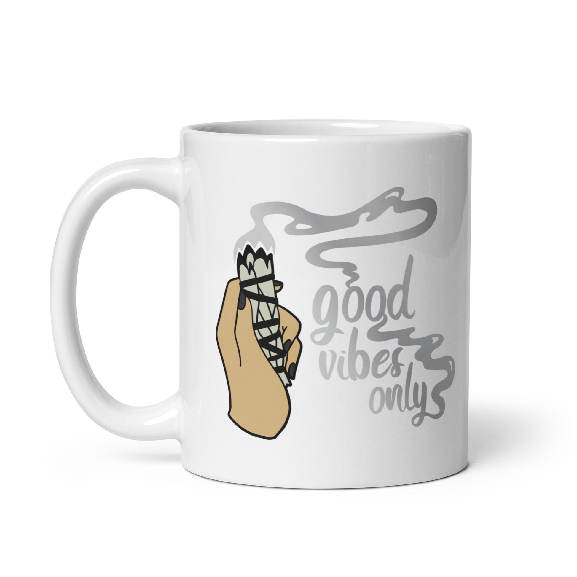 An 11 ounce white ceramic coffee mug featuring an illustration of a hand holding a sage smudge stick. Smoke flows from the tip of the sage and forms words that read "good vibes only"