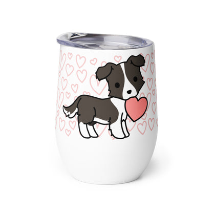 A white metal wine tumbler with a plastic lid. A pattern of hearts wraps around the top half of the tumbler. Centered on the tumbler is a cute, stylized illustration of a Border Collie.