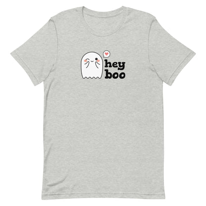 A light heathered grey crewneck t-shirt featuring an image of a cute smiling and blushing ghost. Text alongside the ghost reads "hey boo"