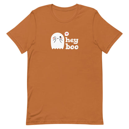 A medium-brown crewneck t-shirt featuring an image of a cute smiling and blushing ghost. Text alongside the ghost reads "hey boo"