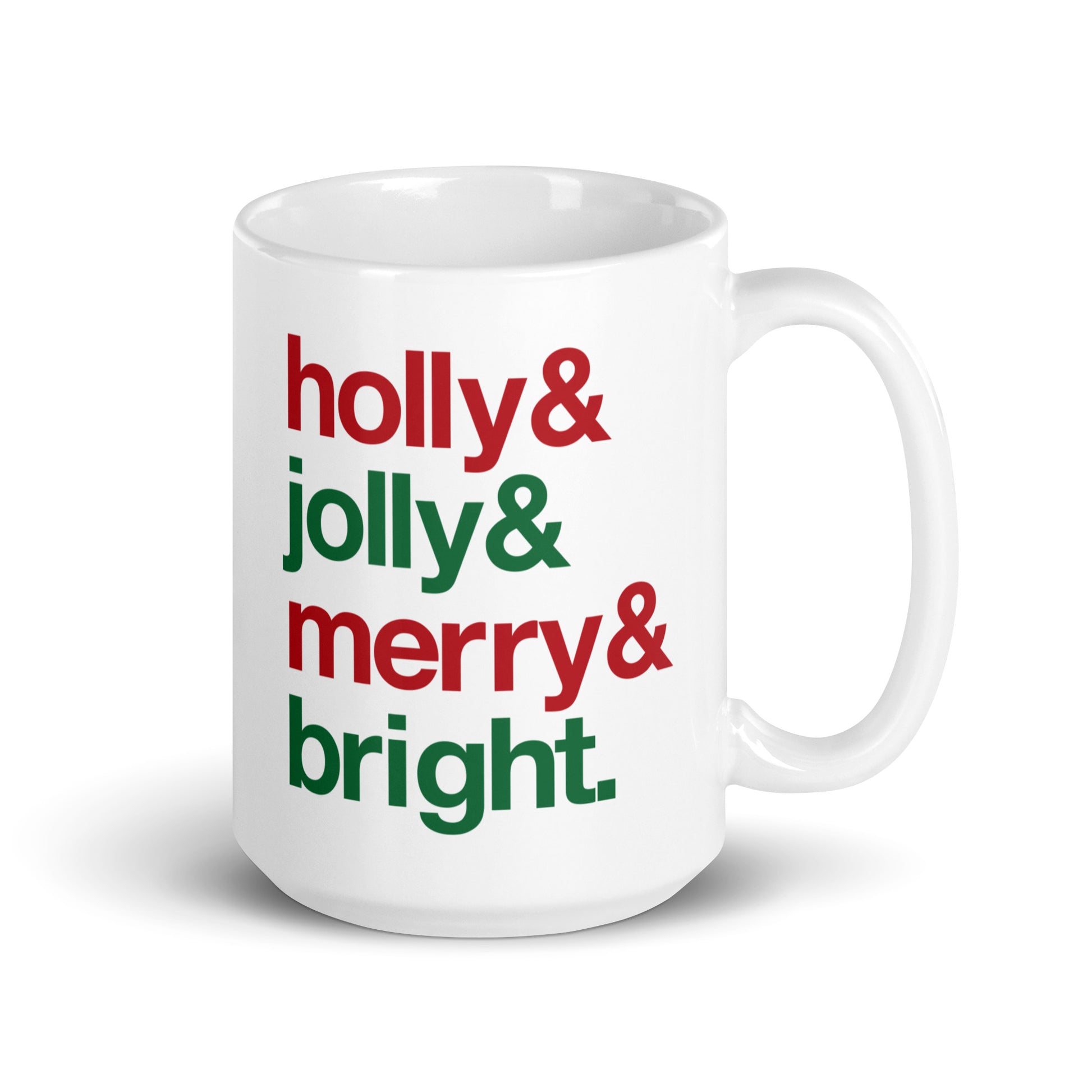 A white 15 ounce ceramic mug with four lines of red and green text that read "Holly & Jolly & Merry & Bright"