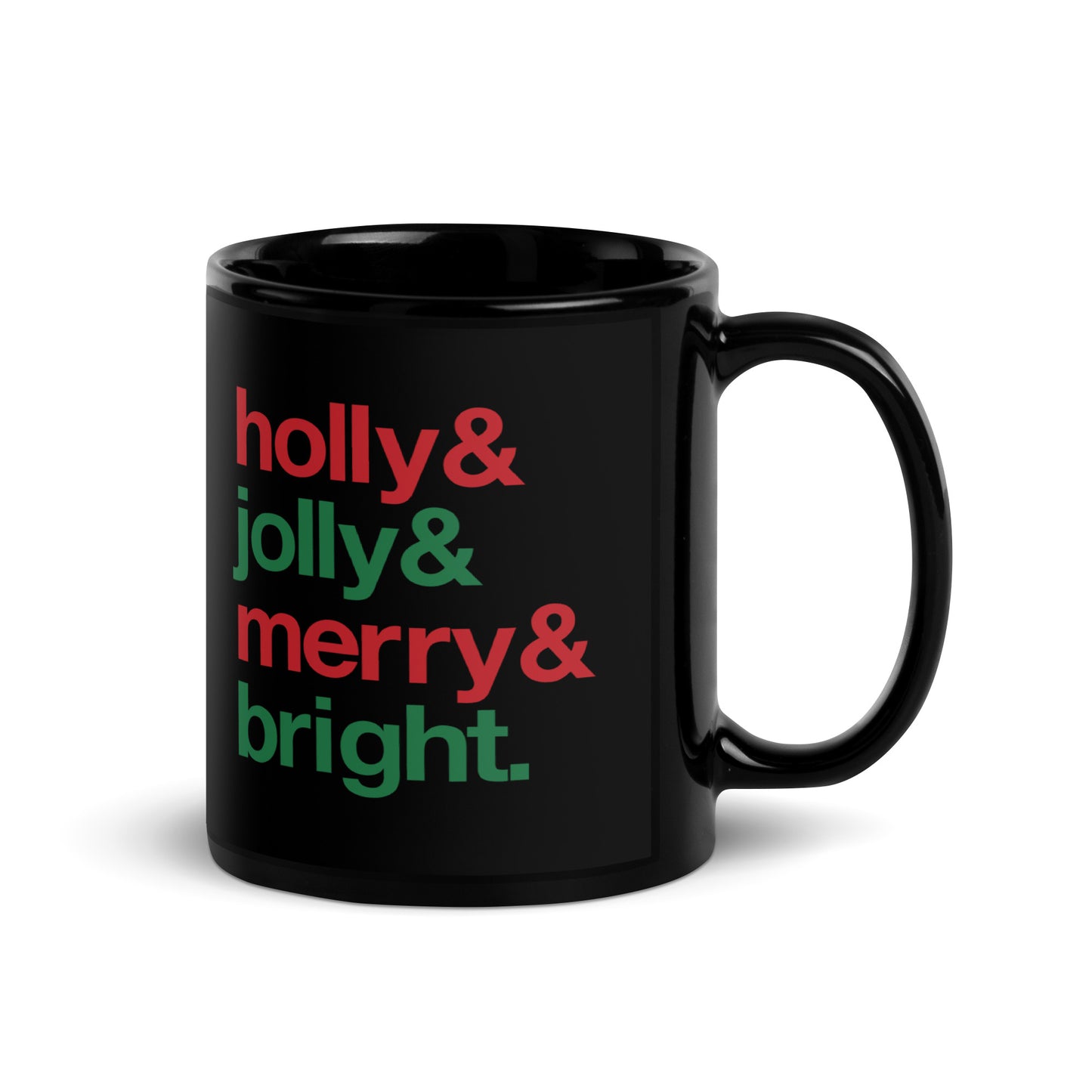 A black 11 ounce ceramic mug with four lines of red and green text that read "Holly & Jolly & Merry & Bright"