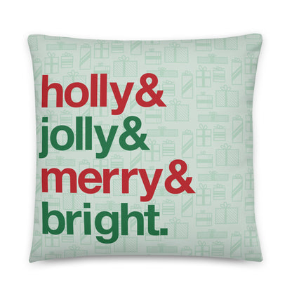 A 22" by 22" throw pillow decorated with a pale green background pattern of presents. There are also four lines of red and green text on the pillow that read "Holly & jolly & merry & bright".
