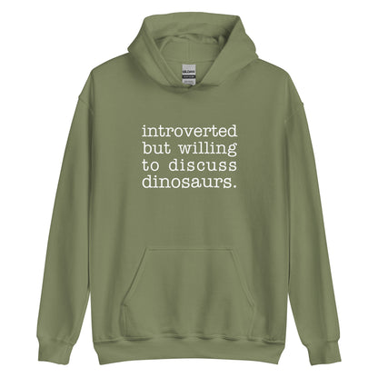 An olive green hooded sweatshirt with white text reading "introverted but willing to discuss dinosaurs"