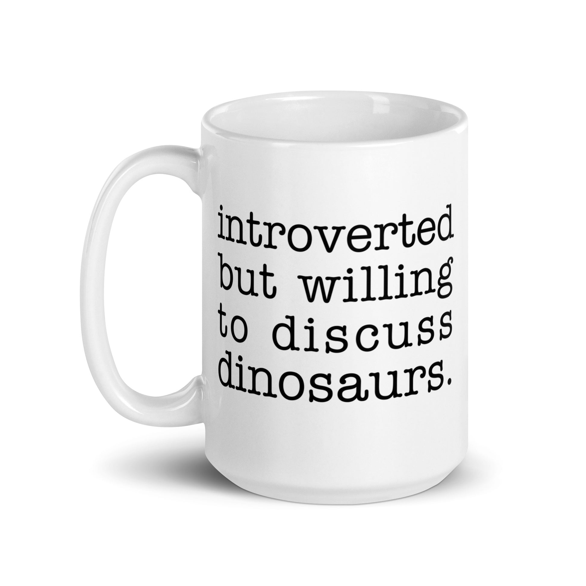 A white 15 ounce ceramic mug with text reading "introverted but willing to discuss dinosaurs"
