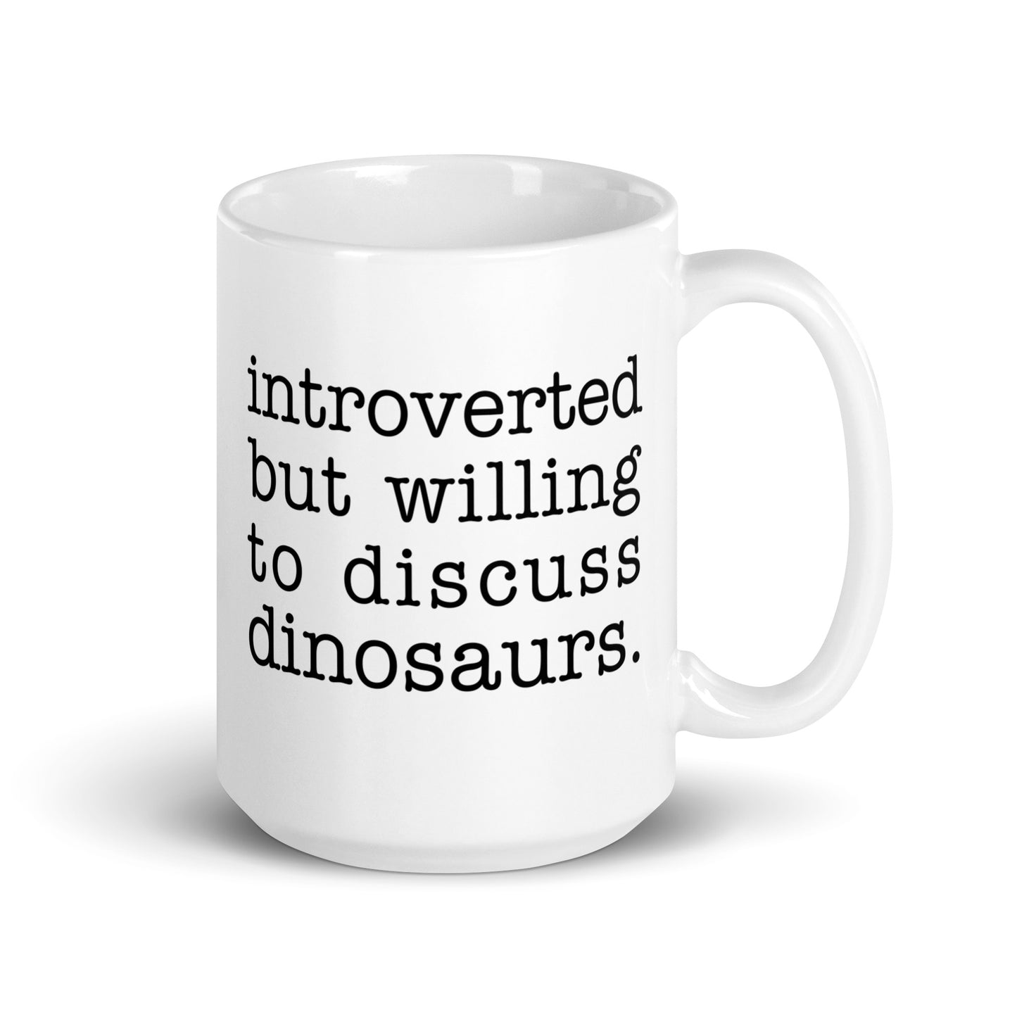 A white 15 ounce ceramic mug with text reading "introverted but willing to discuss dinosaurs"