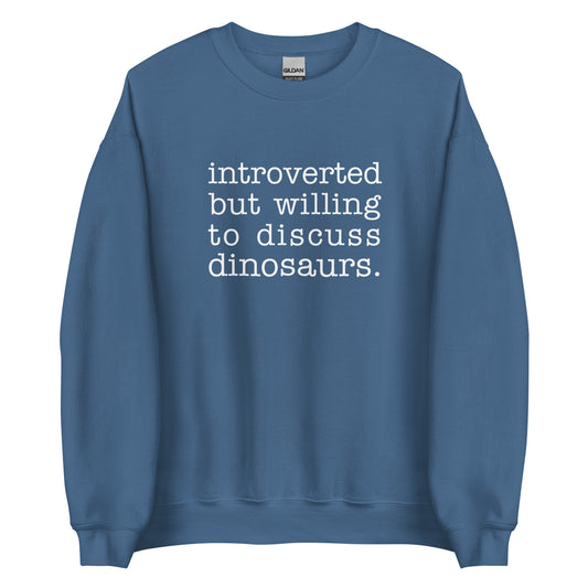 A blue crewneck sweatshirt with white text reading "introverted but willing to discuss dinosaurs"