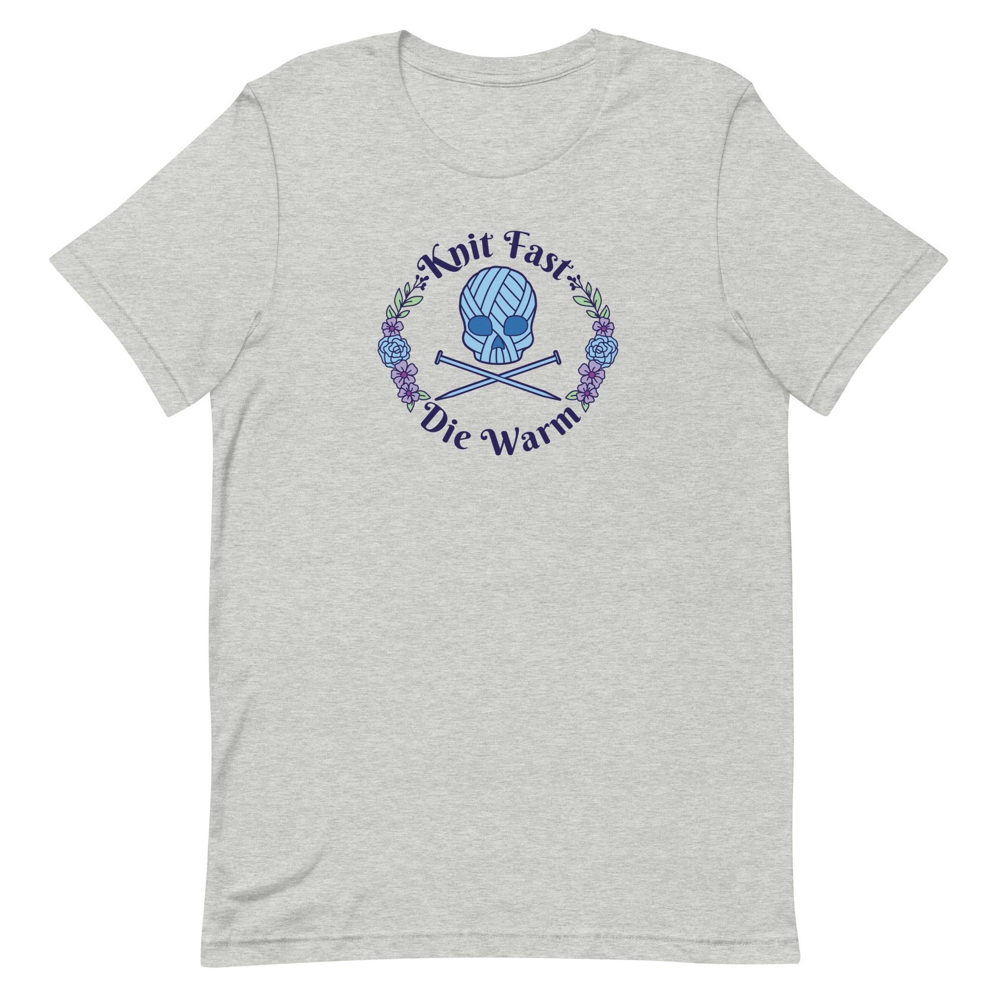 A heather grey crewneck t-shirt featuring an image of a skull and crossbones made of yarn and knitting needles. A floral wreath surrounds the skull, along with words that read "Knit Fast, Die Warm"