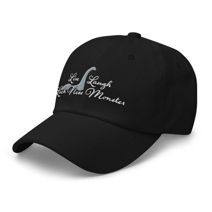 An image of the black baseball cap facing slightly toward the left. White embroidered text decorates the front of the hat reading "Live Laugh Loch Ness Monster" with a silhouette of Nessie.
