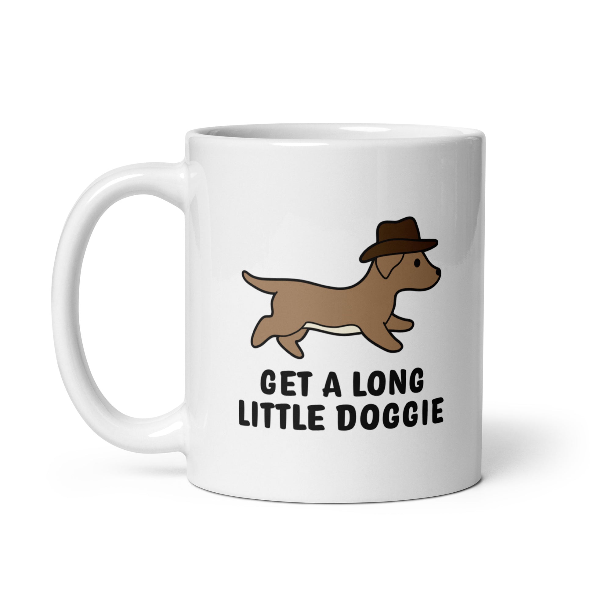 A white 11 ounce ceramic mug featuring an image of a dachshund wearing a cowboy hat. Text below the dog reads "Get a long little doggie"