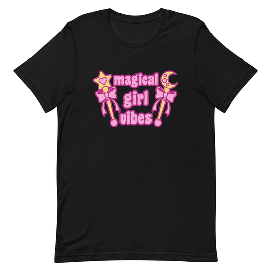 A black crewneck t-shirt featuring two gold wands with pink bows and pink text reading "Magical girl vibes"