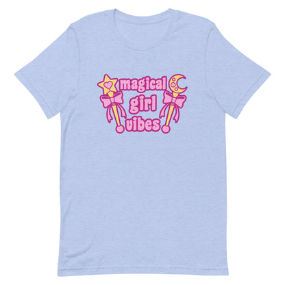 A light blue crewneck t-shirt featuring two gold wands with pink bows and pink text reading "Magical girl vibes"