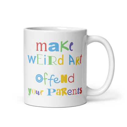 An 11 ounce white ceramic mug featuring text that reads "make weird art, offend your parents" in varying fonts and colors
