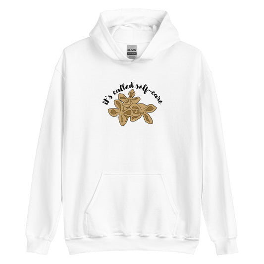 A white hooded sweatshirt featuring an illustration of three pieces of crab rangoon. Text in an arc above the crab rangoon reads "it's called self-care" in a cursive script.