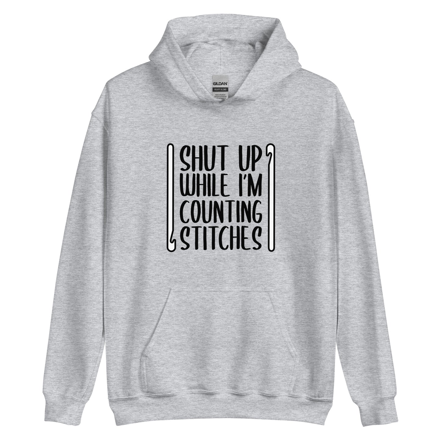 A grey hooded sweatshirt featuring black text that reads "Shut up while I'm counting stitches." The text is framed by a crochet hook to the left and right.