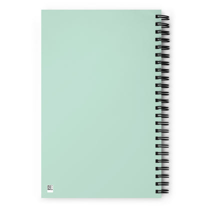 The back side of a mint green o-ring bound notebook.