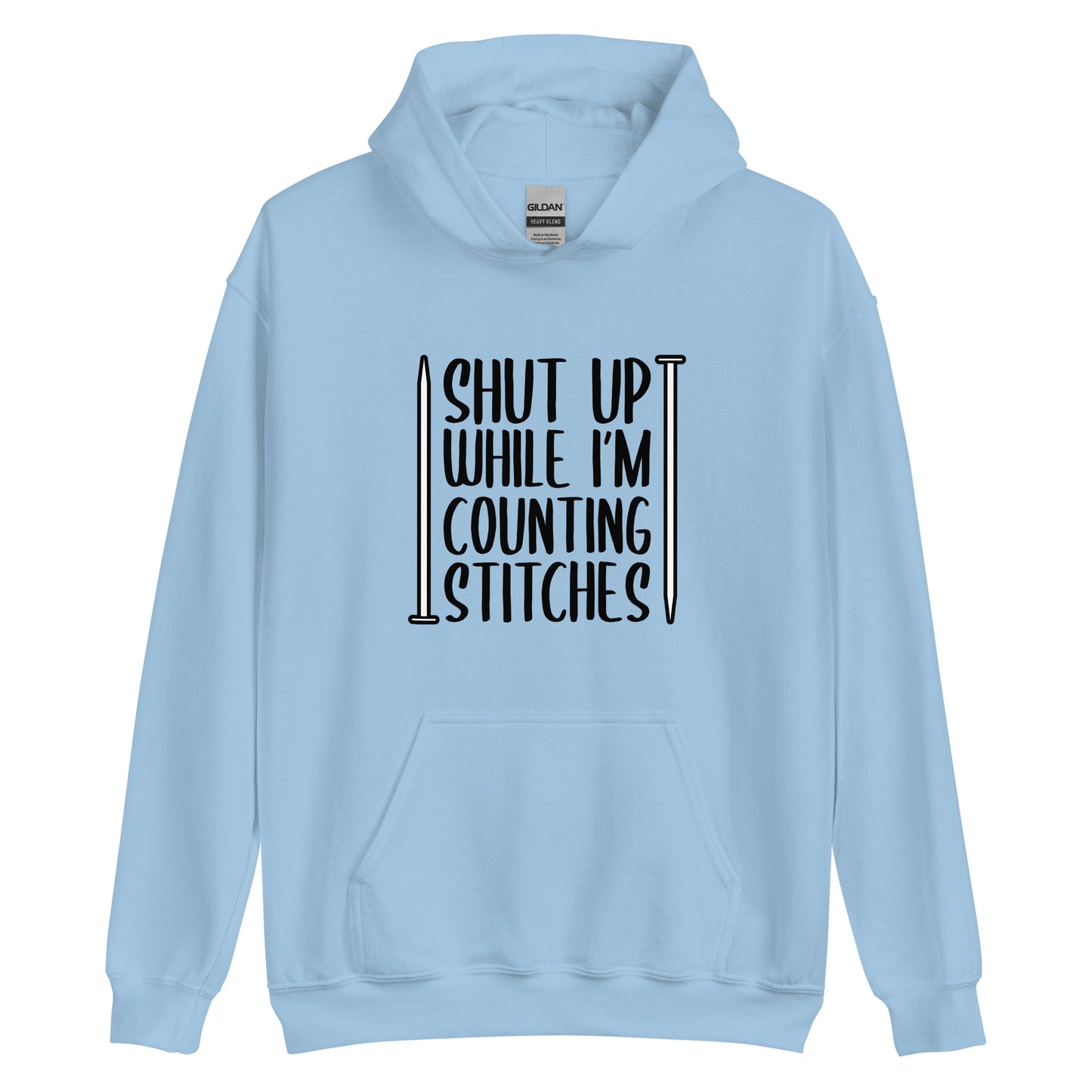 A light blue hooded sweatshirt with black text surrounded by two knitting needles. The text reads "Shut up while I'm counting stiches".